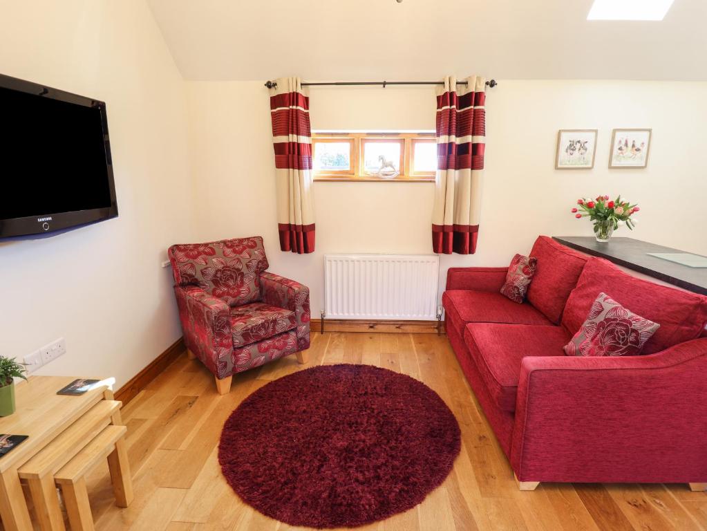 uma sala de estar com um sofá vermelho e uma cadeira em The Stables em Louth