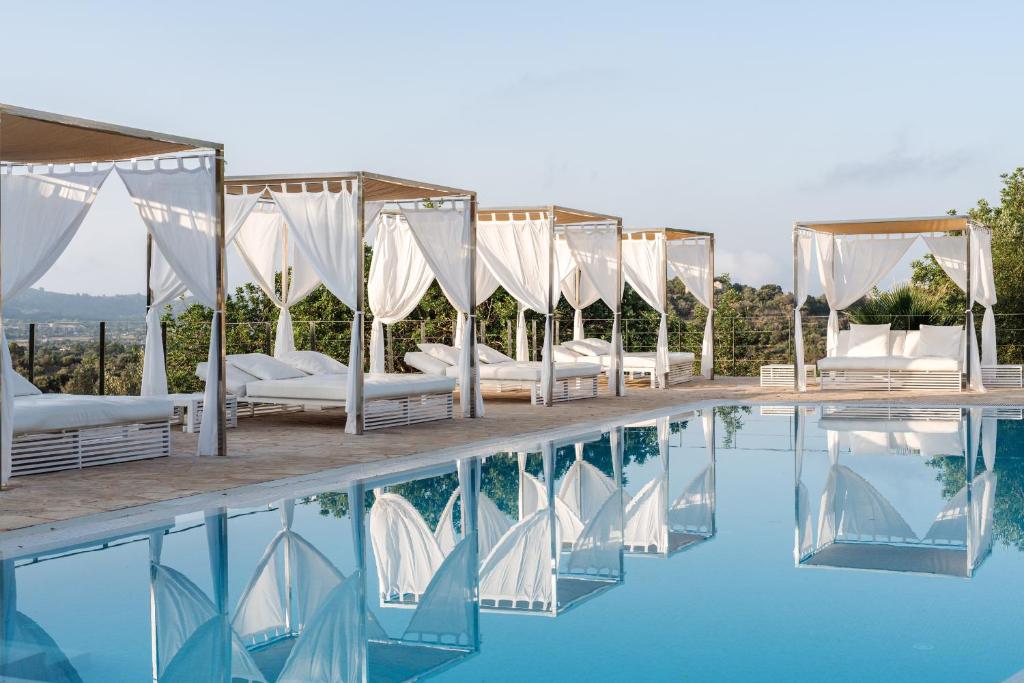 a row of beds next to a swimming pool at Cases de Son Barbassa Hotel & Restaurant in Capdepera