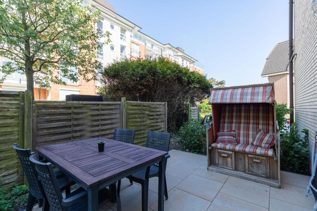 a patio with a table and chairs and a bench at Residenz Meeresbrandung, Whg 39 in Duhnen