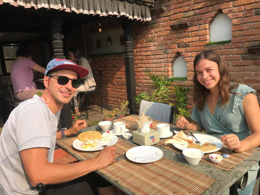 mężczyzna i kobieta siedzący przy stole z jedzeniem w obiekcie Hotel vintage Home w mieście Bhaktapur