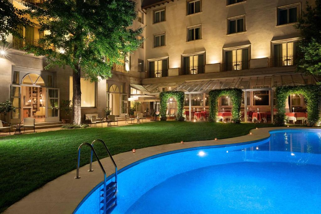 a swimming pool in front of a building at night at Sina Villa Medici, Autograph Collection in Florence