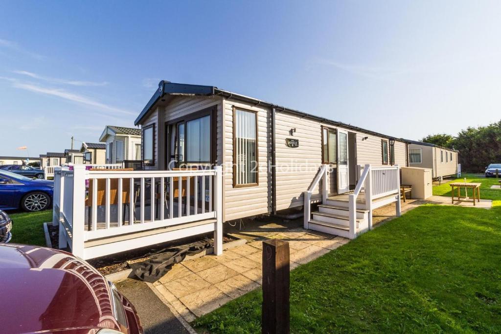 a tiny house with a porch and a yard at Superb 8 Berth Dog Friendly Caravan At Haven Caister In Norfolk Ref 30009d in Great Yarmouth