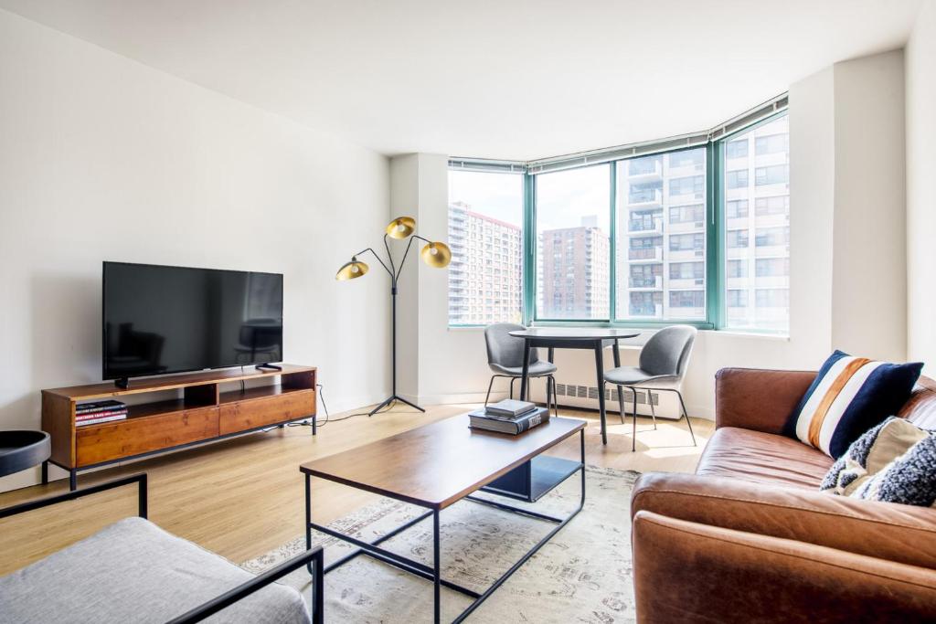ein Wohnzimmer mit einer Couch, einem Fernseher und einem Tisch in der Unterkunft UWS 2BR w Doorman Gym Parking nr Central Park NYC-596 in New York