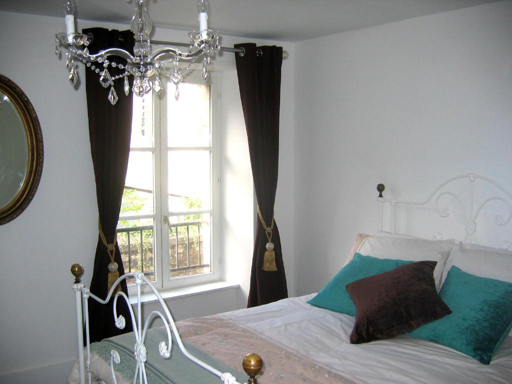 a bedroom with a bed with a chandelier and a window at The Heart of Sainte Mere Eglise in Sainte-Mère-Église
