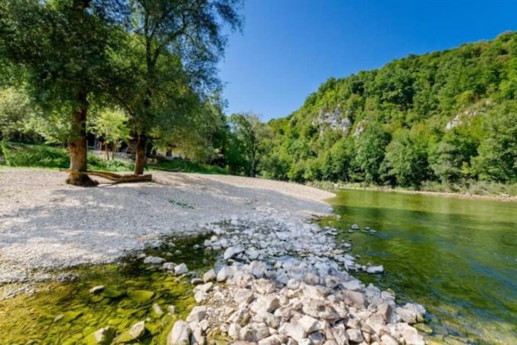 un río con rocas, árboles y una montaña en Cottage near river Kolpa, vineyards,top location., en Adlešiči