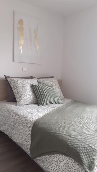 - une chambre blanche dotée d'un lit avec des draps et des oreillers gris dans l'établissement Résidence calme, parking gratuit, à Illzach