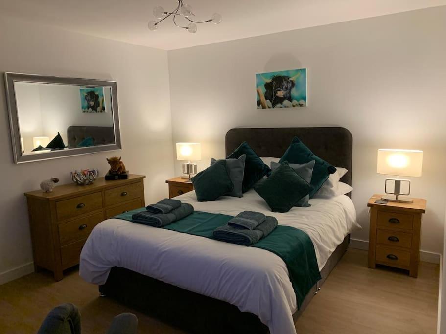 a bedroom with a large bed with green pillows at Cruachan Cabin in Skeabost