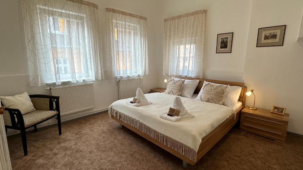 a bedroom with a bed and a chair and windows at Apartment Bohemia in Karlovy Vary