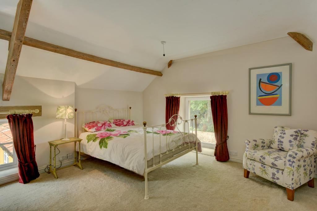 a bedroom with a bed and a chair and a window at Bradford Mill in Tiverton