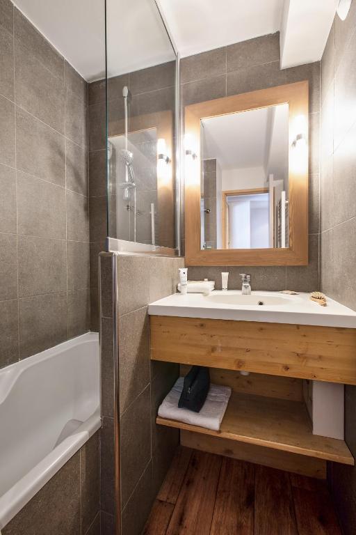 a bathroom with a sink and a tub and a mirror at Résidence Pierre &amp; Vacances Les Néréides in Belle Plagne