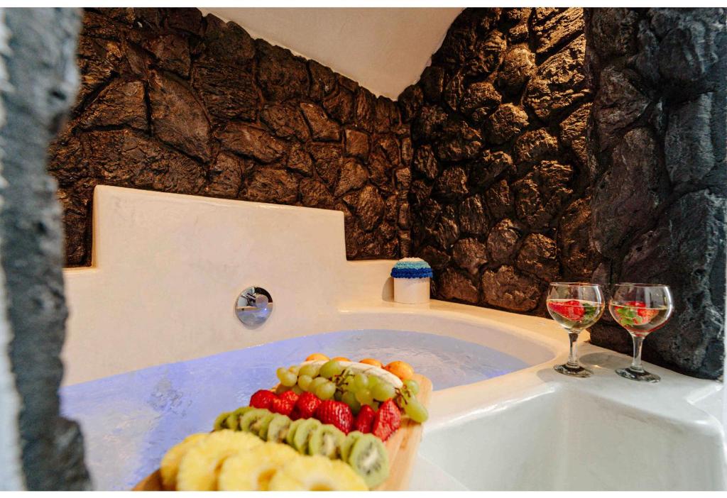 a bath tub with two glasses of wine and fruit in it at aletrivillas in Éxo Goniá