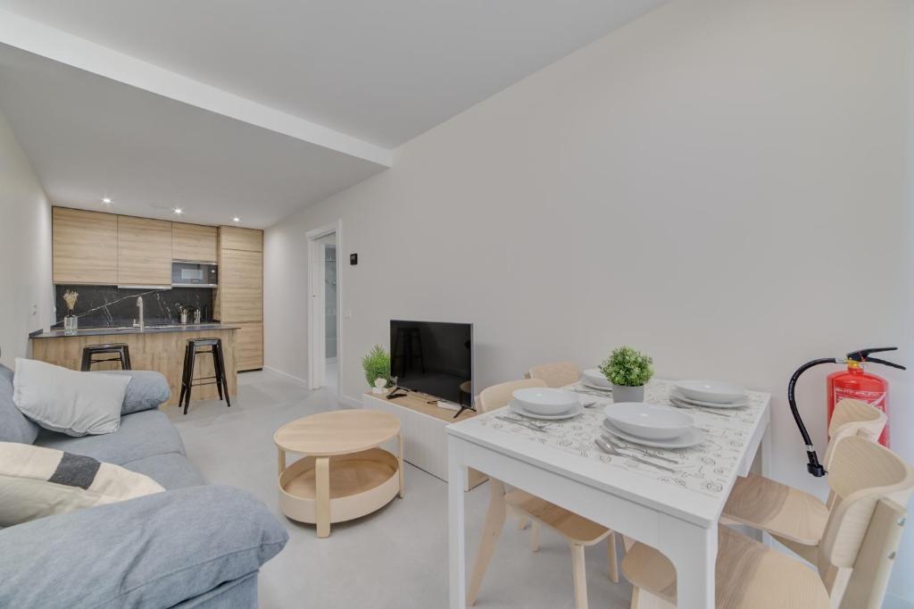 a white living room with a table and a couch at Apartamentos Pamplona Confort by Clabao in Pamplona