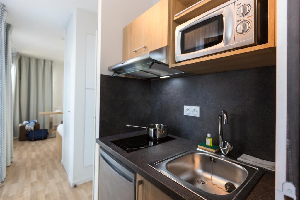 a kitchen with a sink and a microwave at Résidence Odalys Nantes Cité des Congrès in Nantes