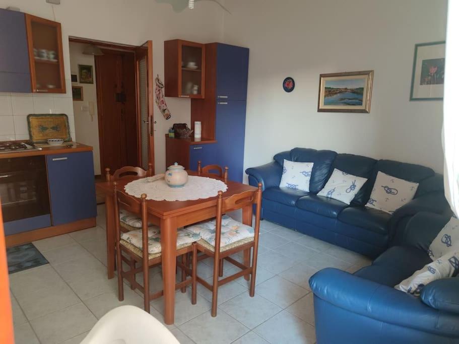un soggiorno con un tavolo e un divano blu di Alghero, ottimo appartamento a 100 m. dal mare ad Alghero