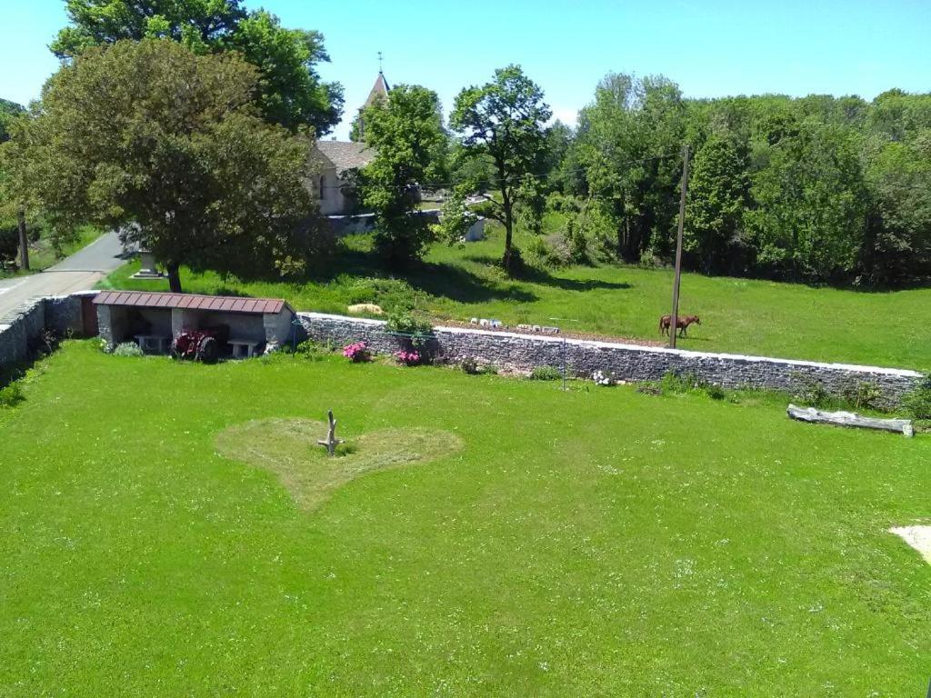 een groene tuin met een stenen muur en een gebouw bij Autrefois la Cure in Bonnefontaine