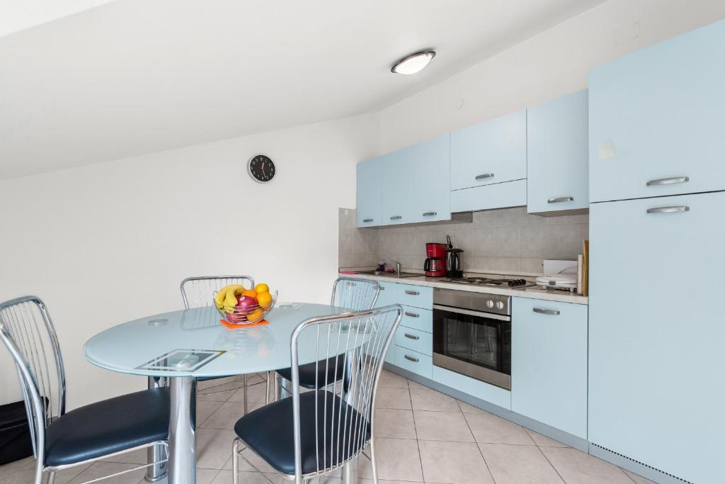 a kitchen with white cabinets and a table and chairs at Apartment Luna in Poreč