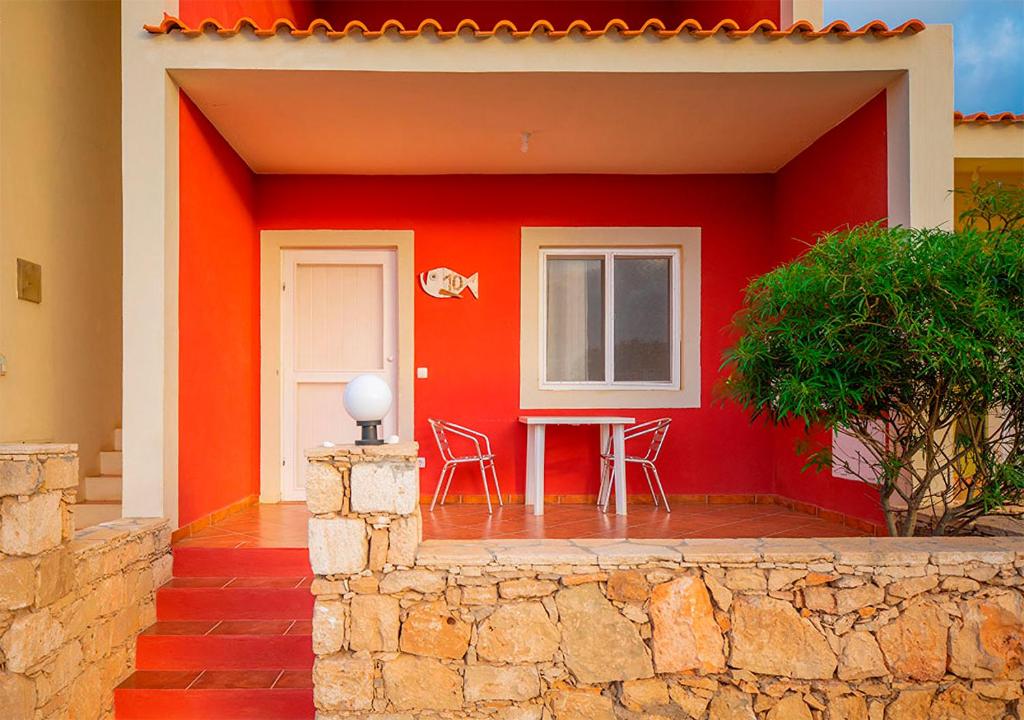 a red wall of a house with a table and chairs at Appartamento Garroupa. Stella Maris Exclusive in Vila do Porto