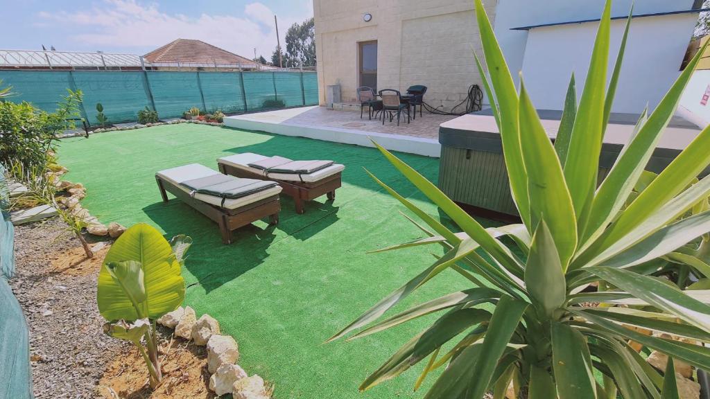 einen Hinterhof mit einer Liegewiese mit Tischen und Stühlen in der Unterkunft STAY Pernera House in Ayia Napa