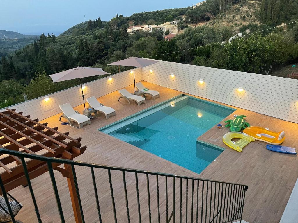 a swimming pool on a deck with chairs and an umbrella at Angelo’s villa in Avliótai