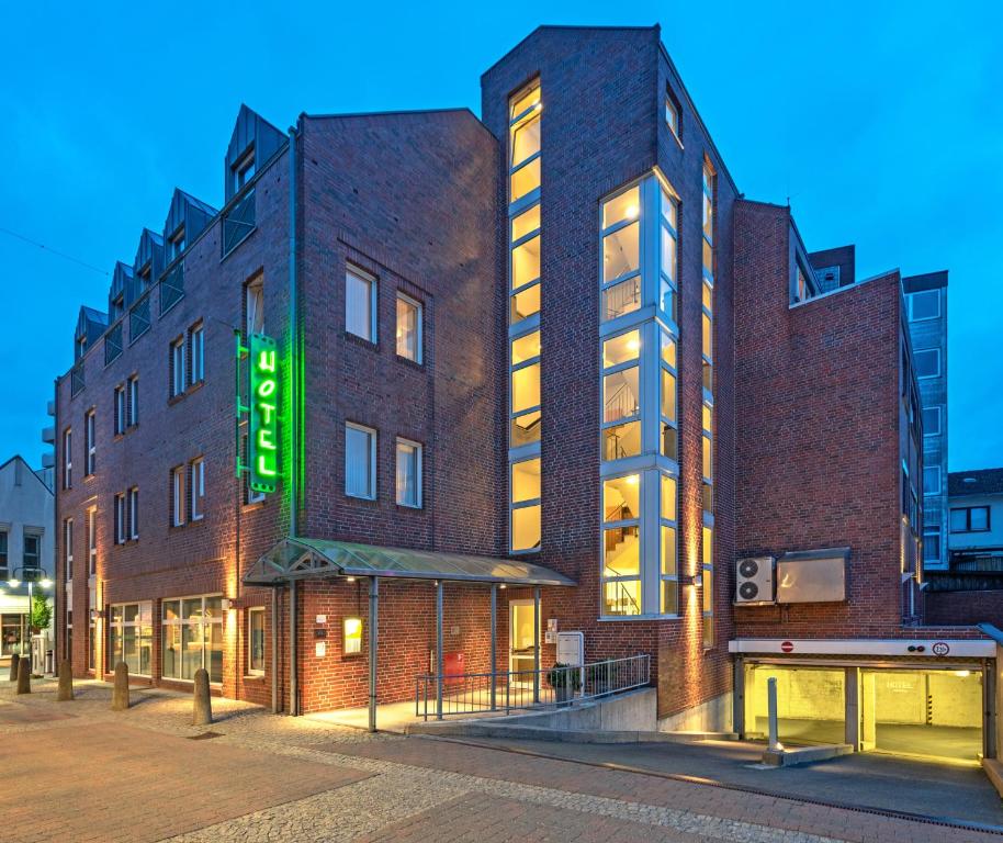 un edificio de ladrillo con una señal verde. en HOTEL BREMER TOR, Bestes Hotelfrühstück, Self-Check-In 24 h, en Vechta