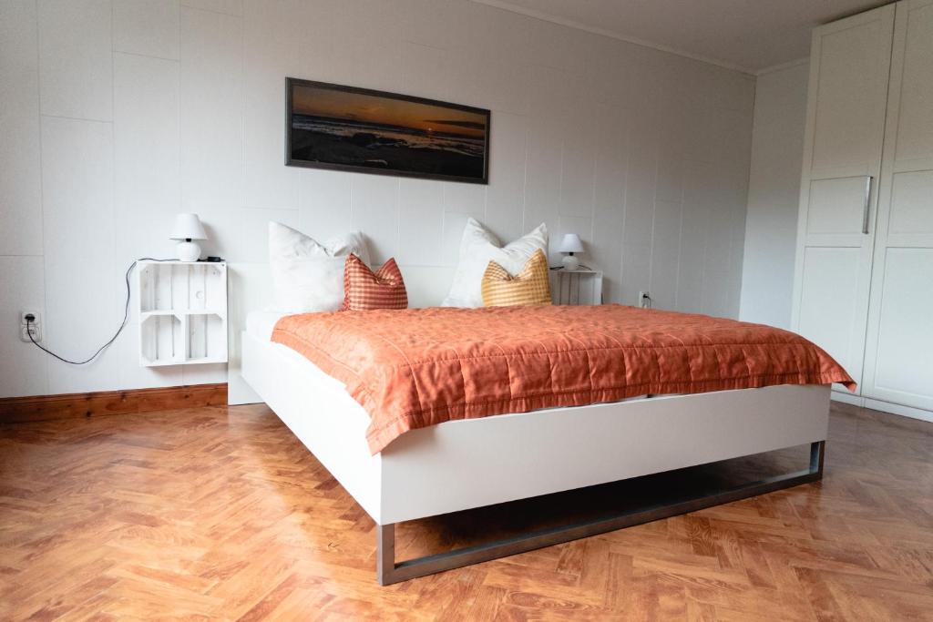 biała sypialnia z łóżkiem z pomarańczową kołdrą w obiekcie Zimmerfrei-Barz w mieście Ahlefeld