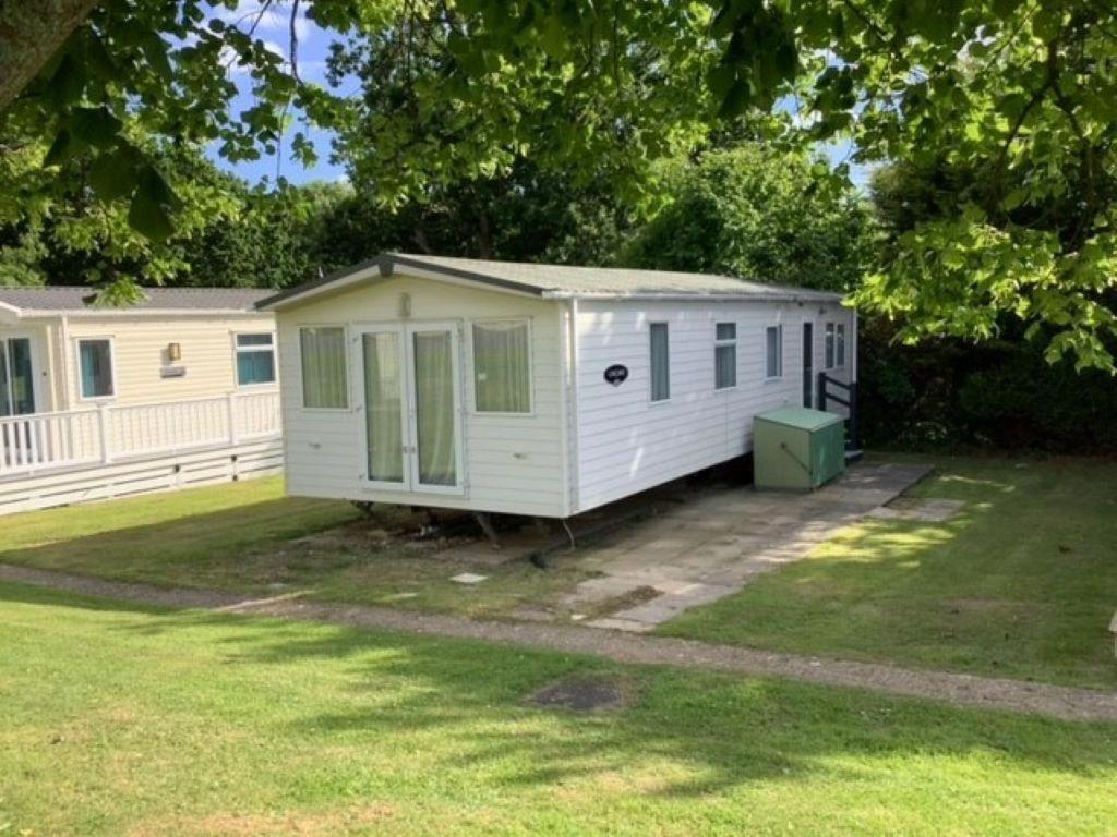 a white mobile home in a yard at Beautiful 6 Berth Caravan With Wifi In Hampshire Ref 81337sb in Milford on Sea