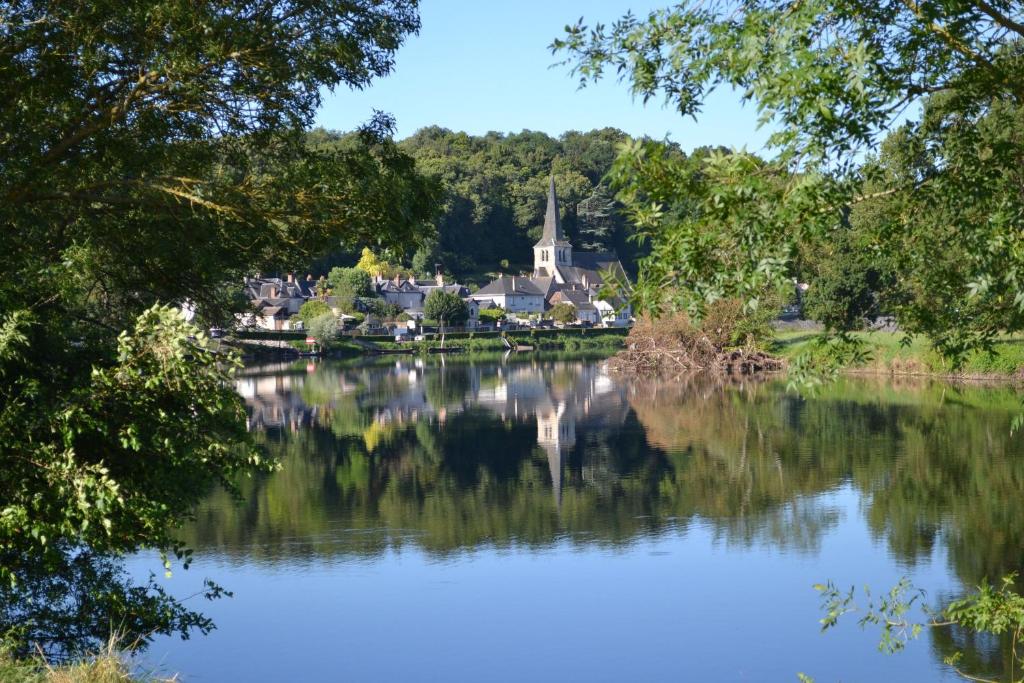 a village on the shore of a lake with a church at Gîte au bord du Cher "La Mésange Verte" in Savonnières