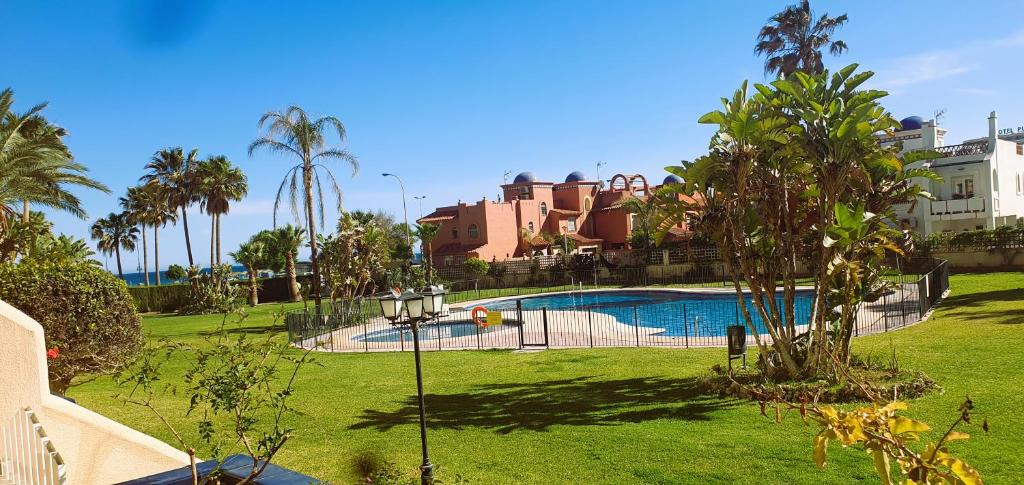 una piscina en un patio con palmeras y edificios en Vive la vida: Torremolinos (1ª línea) en Torremolinos