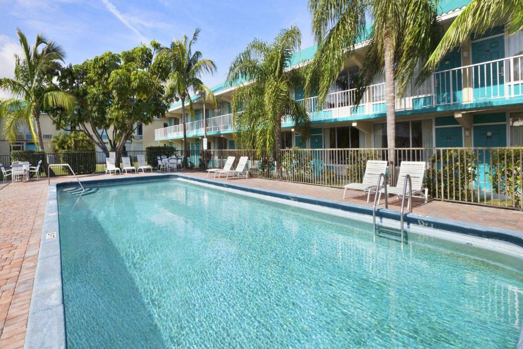 a swimming pool in front of a building with palm trees at Days Inn by Wyndham Fort Pierce Midtown in Fort Pierce