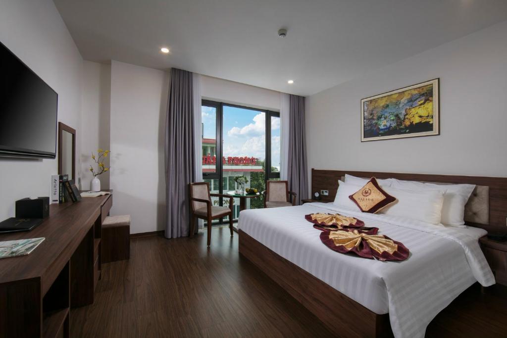 ハロンにあるHalios Luxury Halong Hotelの大きなベッドとデスクが備わるホテルルームです。