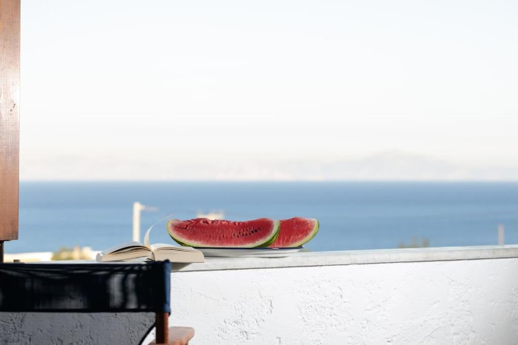 two slices of watermelon sitting on a counter next to a book at "Triacanthos" 3 bedroom house in Moutsoúna