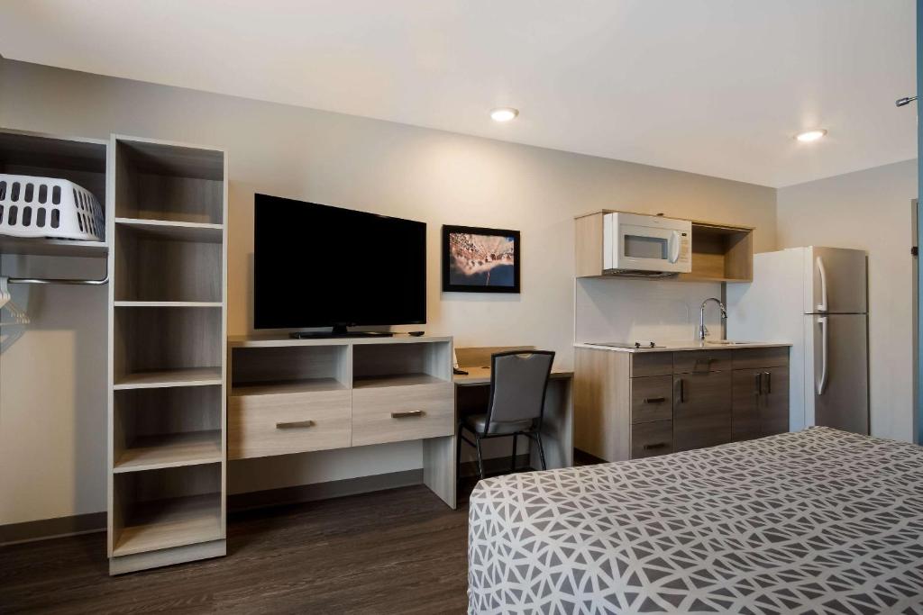 Un dormitorio con una cama y un escritorio con televisión. en WoodSpring Suites Grand Rapids Kentwood, en Grand Rapids