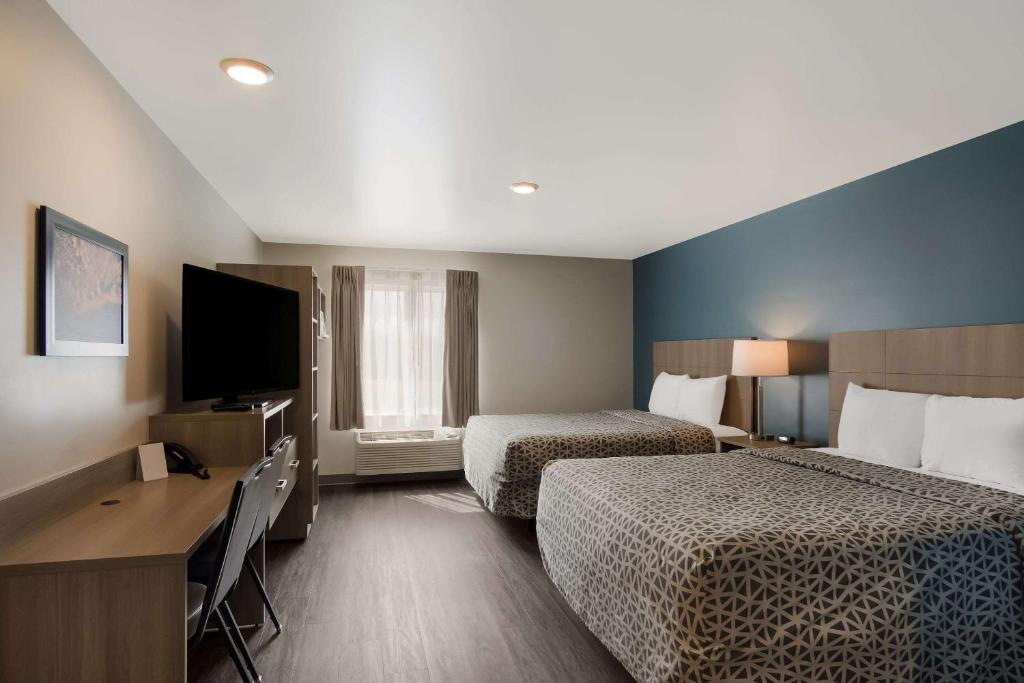 WoodSpring Suites Grand Rapids Kentwood في غراند رابيدز: غرفة فندقية بسريرين وتلفزيون بشاشة مسطحة