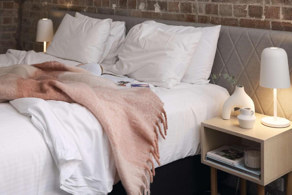 Una cama con almohadas blancas y una manta. en The Ultimo, en Sídney