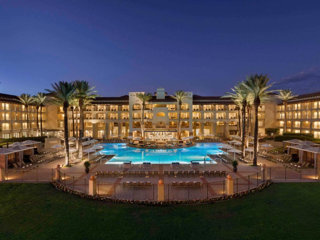 a large building with a large swimming pool with palm trees at Fairmont Scottsdale Princess in Scottsdale