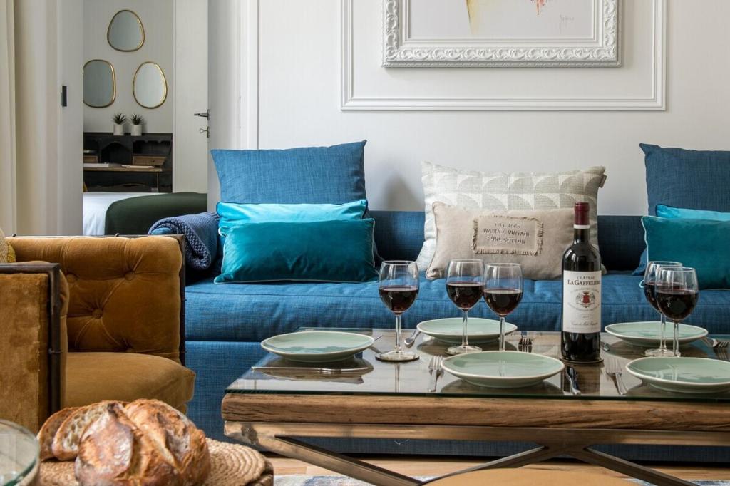 a living room with a blue couch and wine glasses at My Opéra II in Paris
