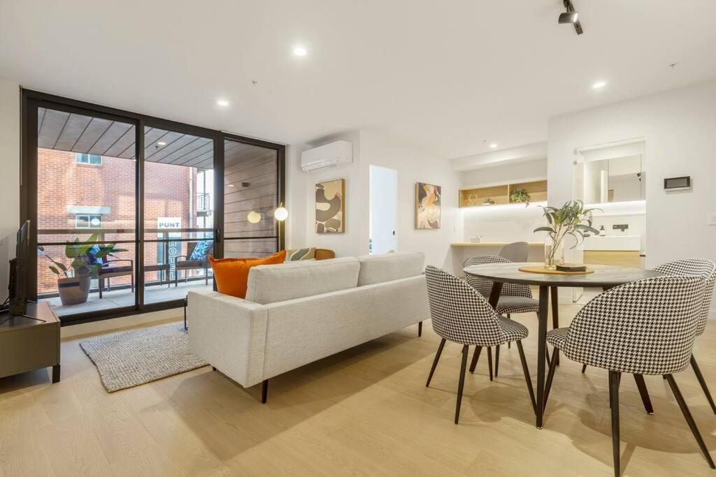 een woonkamer met een bank en een tafel en stoelen bij Nice 2-bed rental unit with free parking in Melbourne