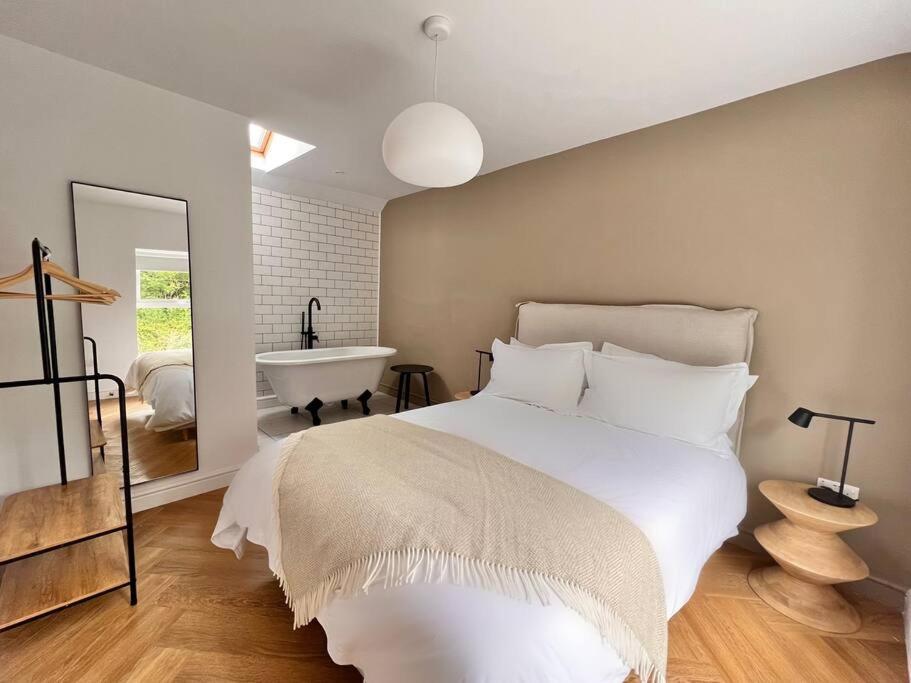 1 dormitorio con 1 cama grande y bañera en A Beautiful 3 Bedroom 17th Century Stone cottage en Llanddyfnan