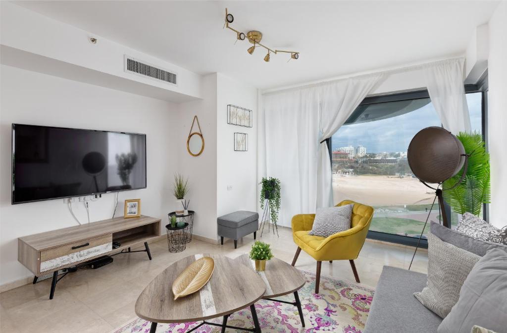 un soggiorno con TV e ampia finestra di Dream Suite by the beach - Parking & Pool & Gym a Herzliya B