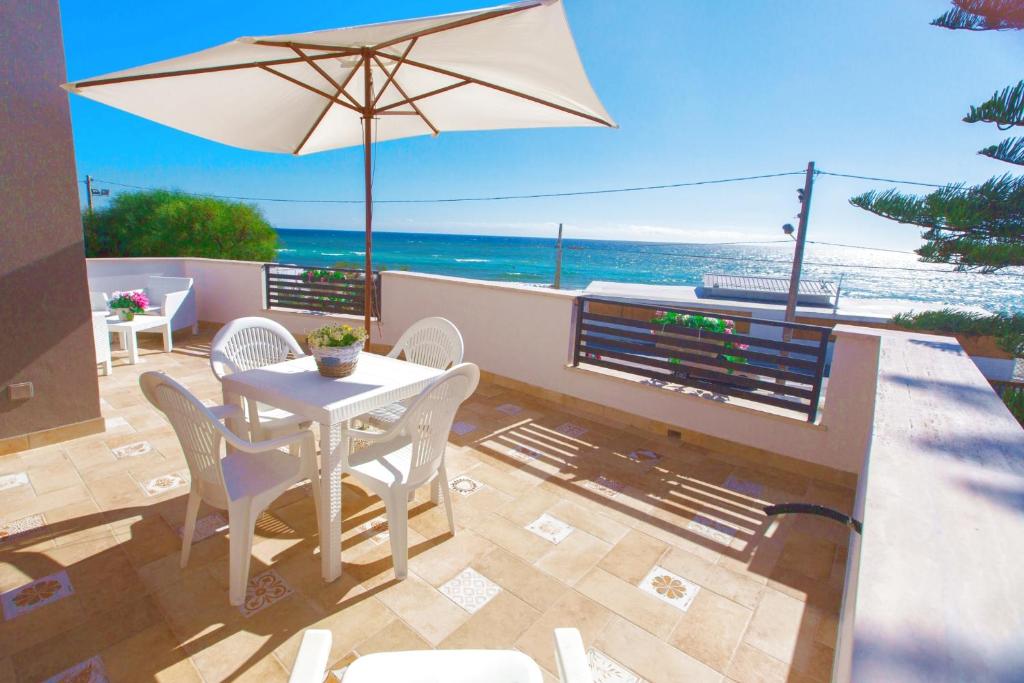 un patio con mesa, sillas y sombrilla en Villa Blue Sea - Xenia Sicily Villas, en Mazara del Vallo