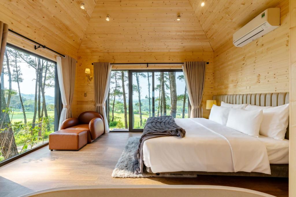 a bedroom with a bed and a large window at Trang An Golf and Resort 