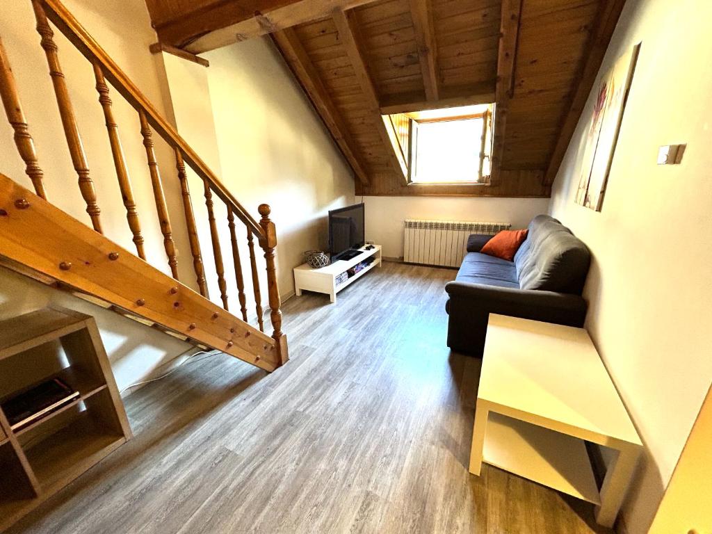 sala de estar con sofá y escalera en Dúplex lluminós a Esterri d'Àneu by RURAL D'ÀNEU, en Esterri d'Àneu