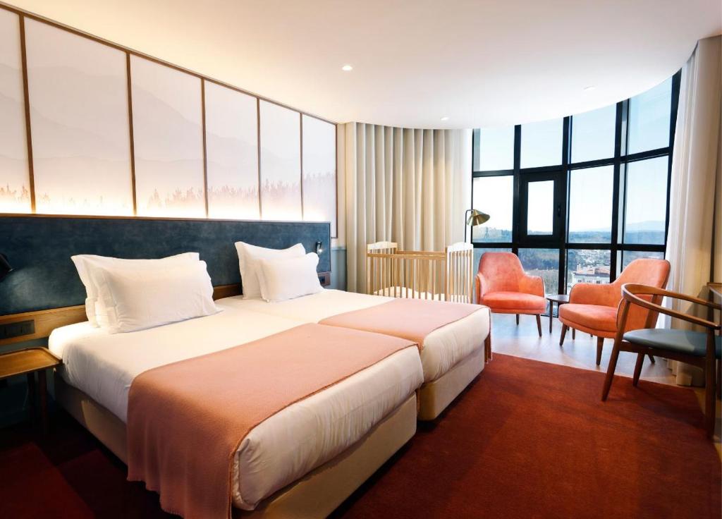 ヴィゼウにあるモンテベロ ヴィゼウ コングレス ホテルの大きなベッドと椅子が備わるホテルルームです。