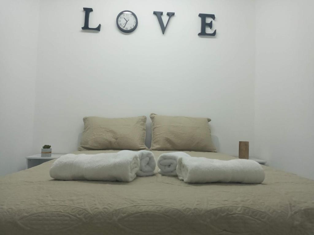 łóżko z 2 poduszkami i zegarem na ścianie w obiekcie רימון יחידות אירוח Vacation units RIMON w mieście Aszkelon