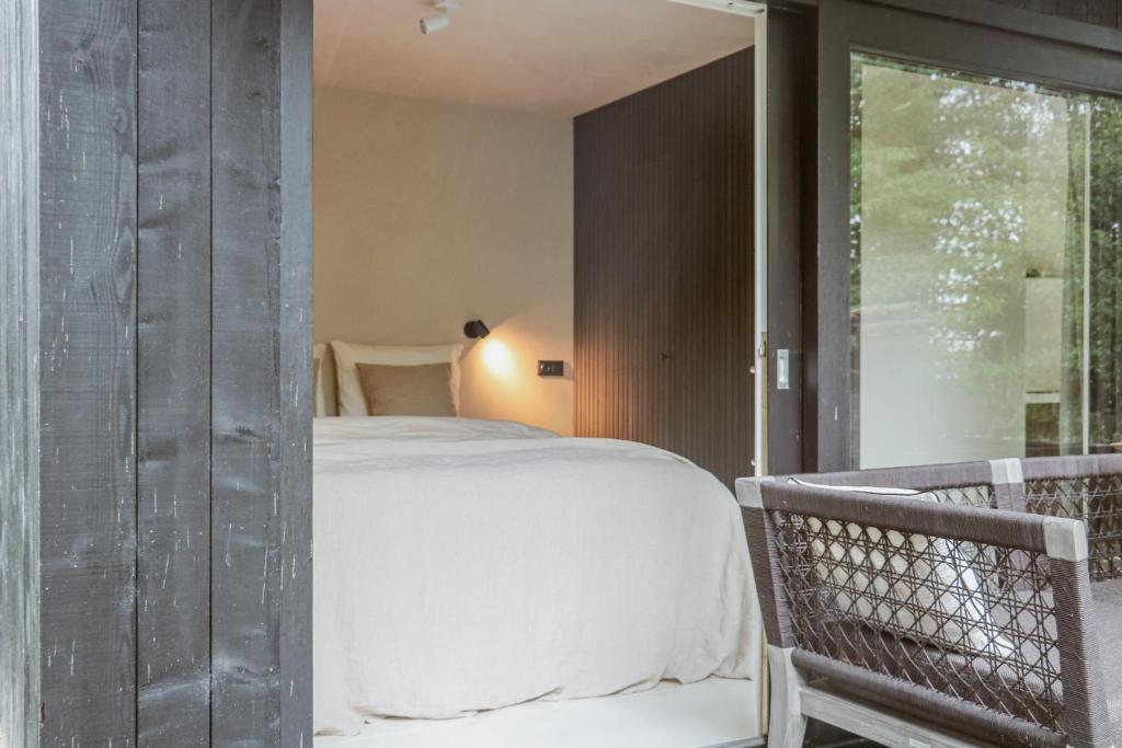 a bedroom with a large white bed next to a window at Cabin Water Zuidermeer in Zuidermeer