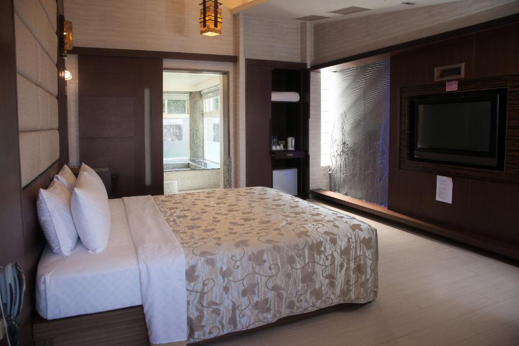 a hotel room with a bed and a television at Guanziling Lin Kuei Yuan Hot Spring Resort in Baihe