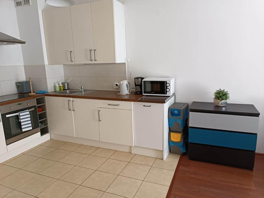 eine Küche mit weißen Schränken und einer Mikrowelle in der Unterkunft Platan 3 in Świnoujście