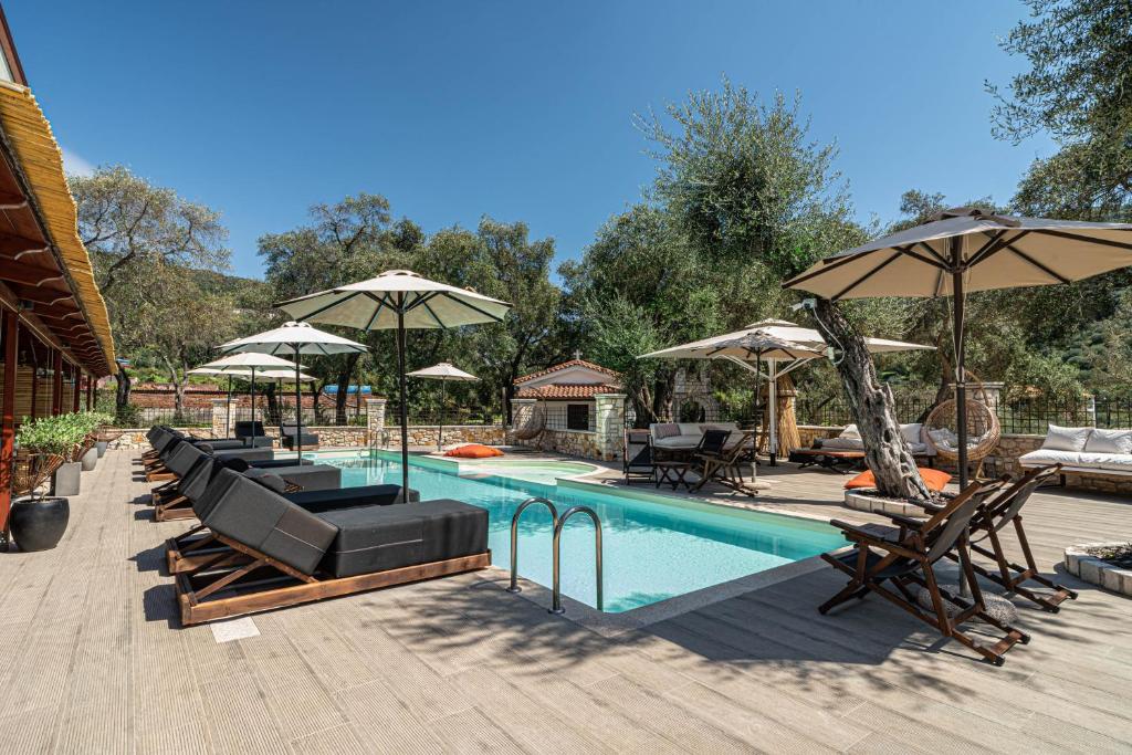 a swimming pool with chairs and umbrellas at F & S LOUNGE SUITES in Parga