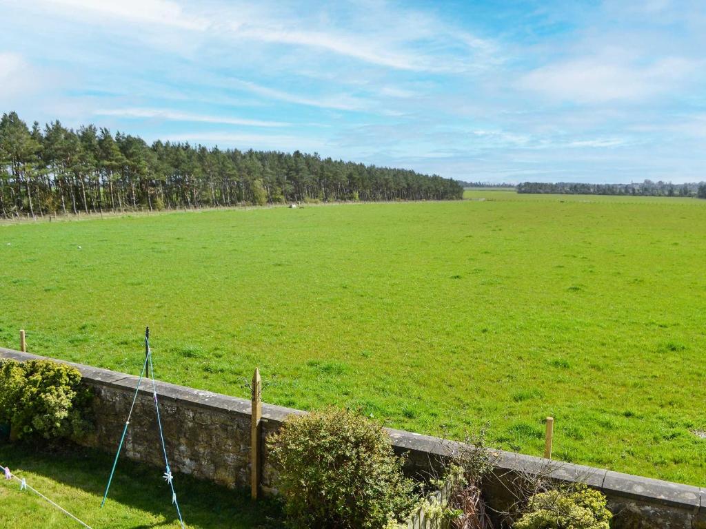 a large green field with trees in the distance at Low Chibburn Farm Cottage in Hadston