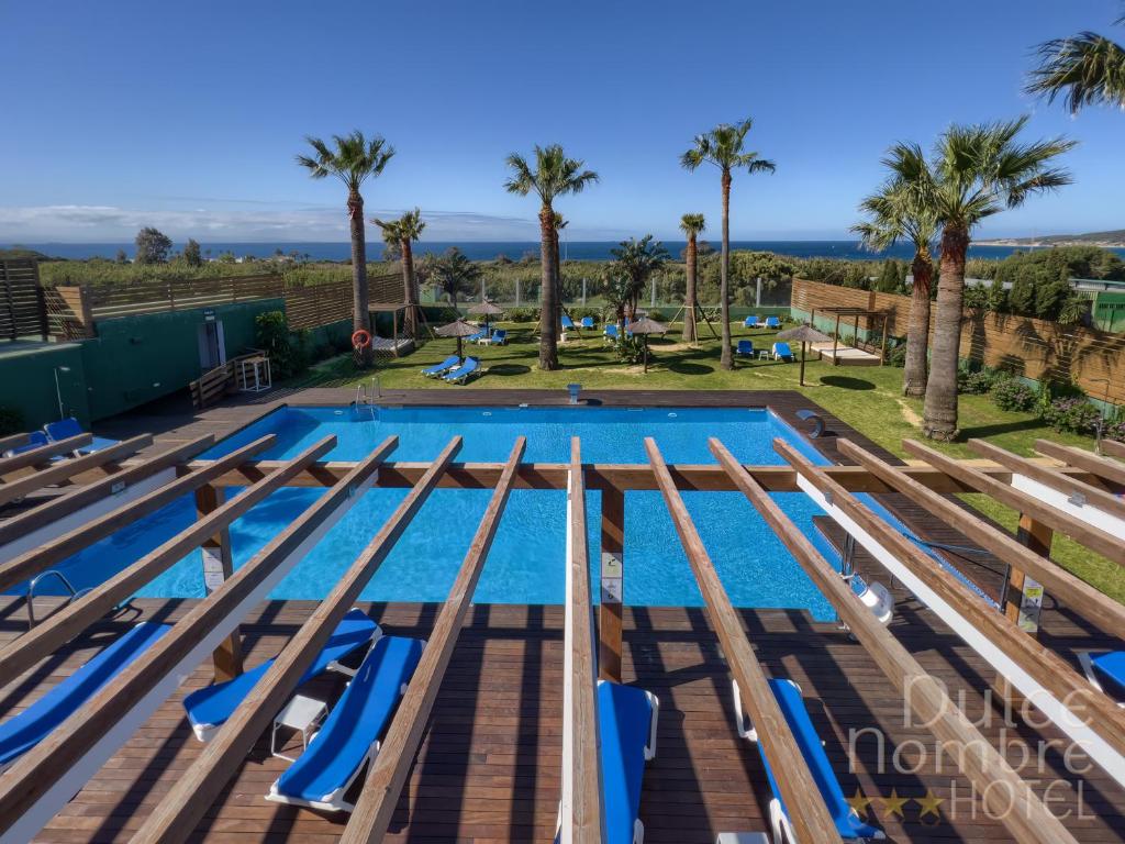 ein Bild eines Pools mit blauen Stühlen und Palmen in der Unterkunft Dulce Nombre Tarifa in Tarifa